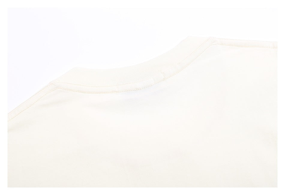 Close-up of an off-white garment's ribbed crew neckline and shoulder stitching.