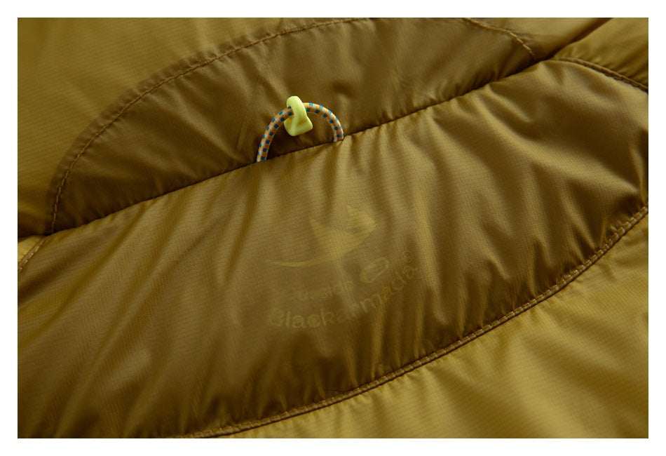 Close-up of a mustard-yellow garment showing a cord loop, neon toggle, and faint printed logo.
