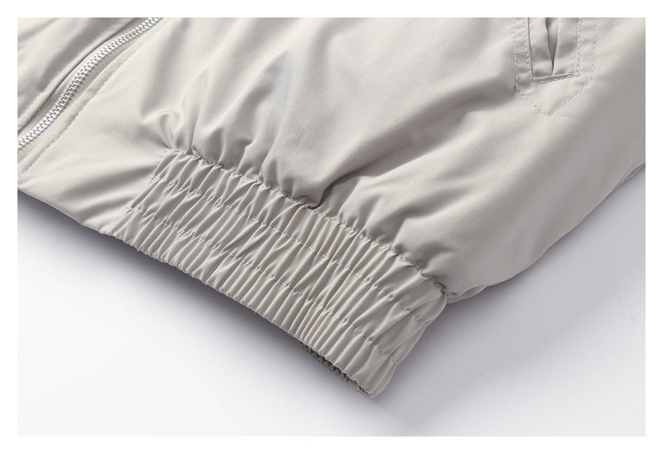 Close-up of a light gray jacket's gathered elastic hem and pocket detail.