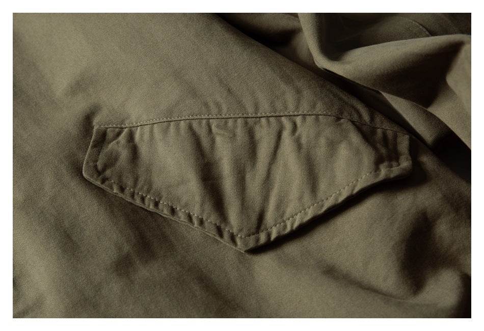 Close-up of a stitched flap pocket on the olive jacket.