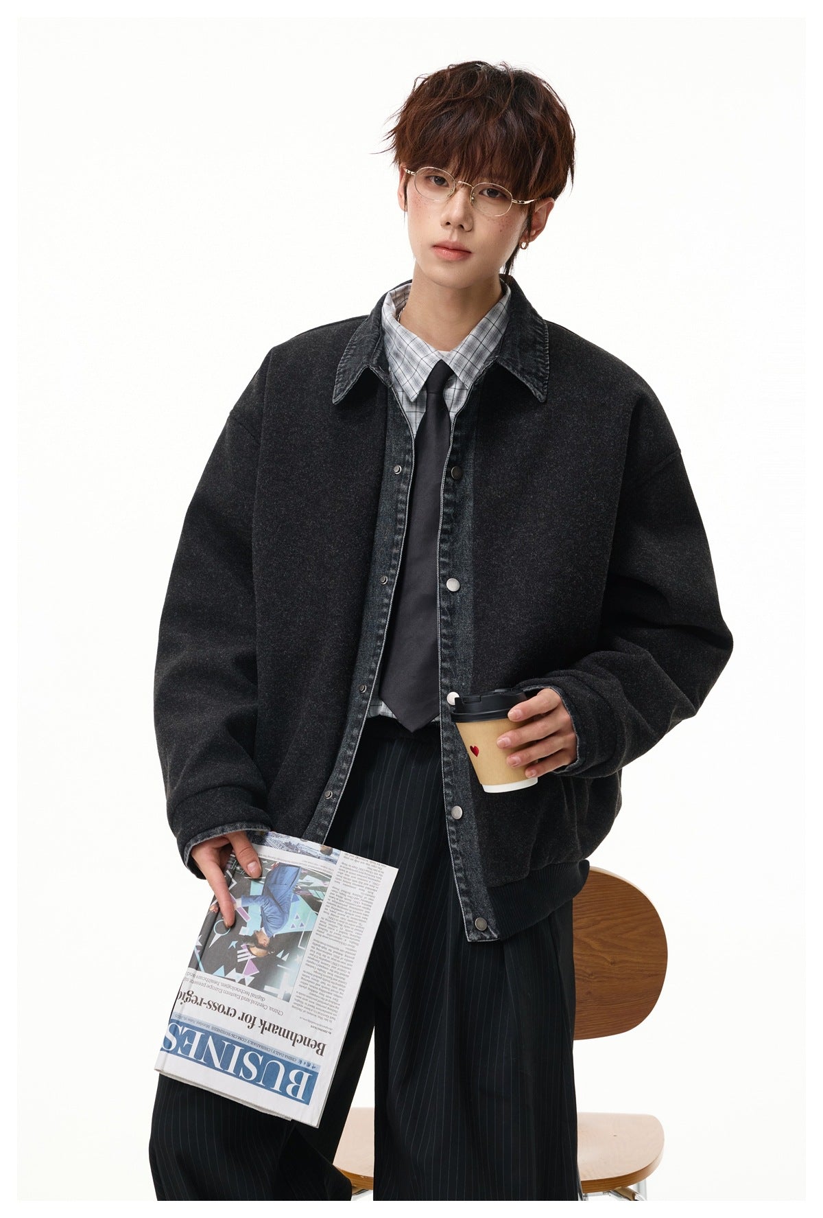 Model wearing a dark charcoal jacket with a washed denim collar and snap front, styled with a plaid shirt and black tie.