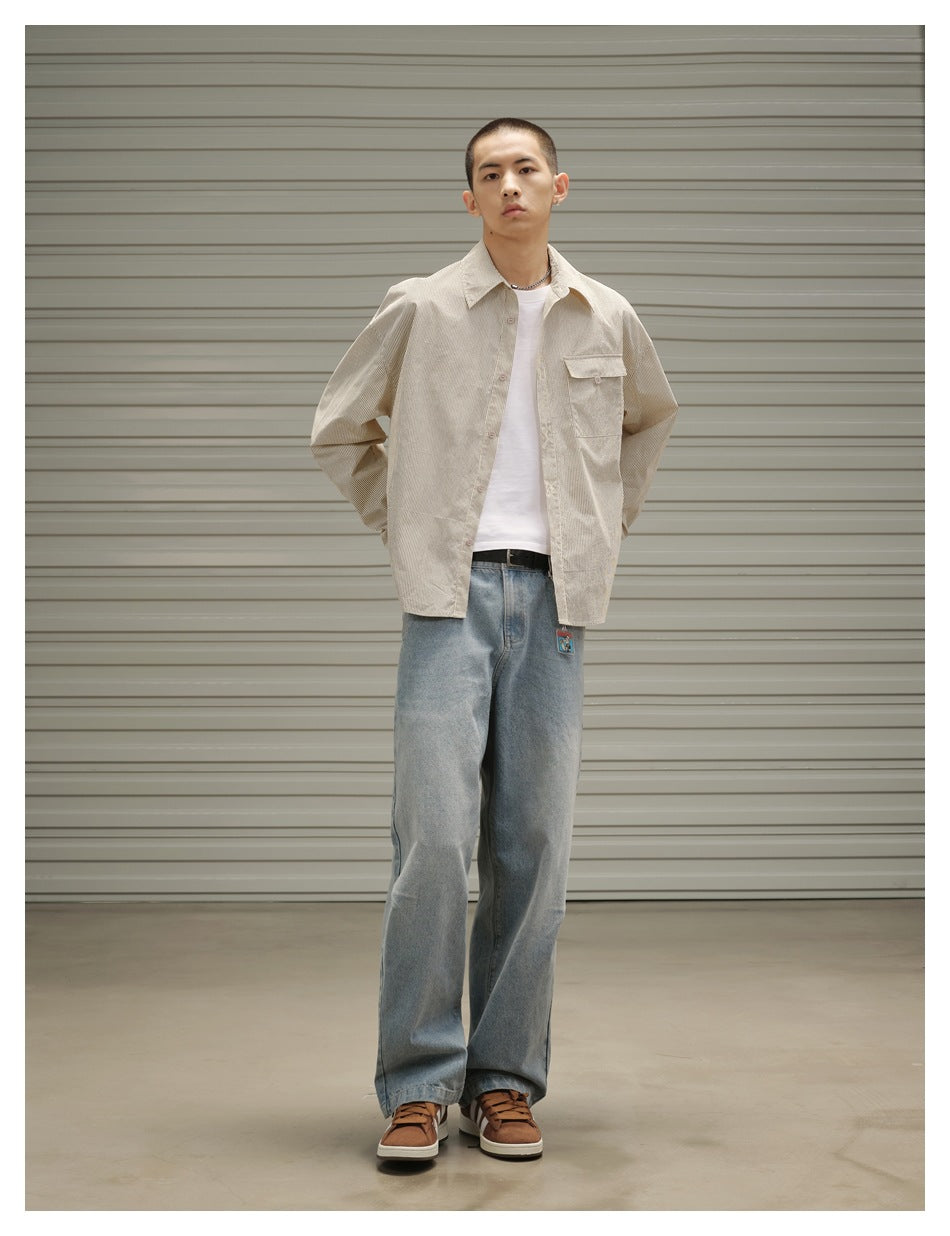 Model wearing a light beige button-front overshirt over a white tee with pale blue wide-leg jeans.