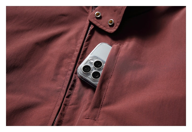 Close-up of a burgundy jacket's narrow chest pocket holding a smartphone.