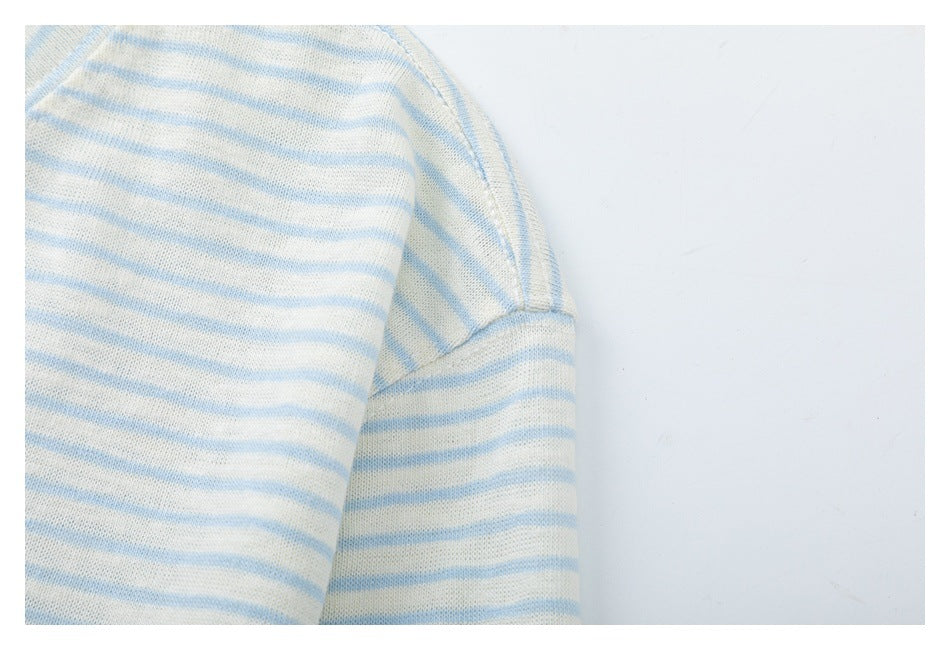 Close-up of a cream garment with pale blue horizontal stripes and a curved stitched seam.
