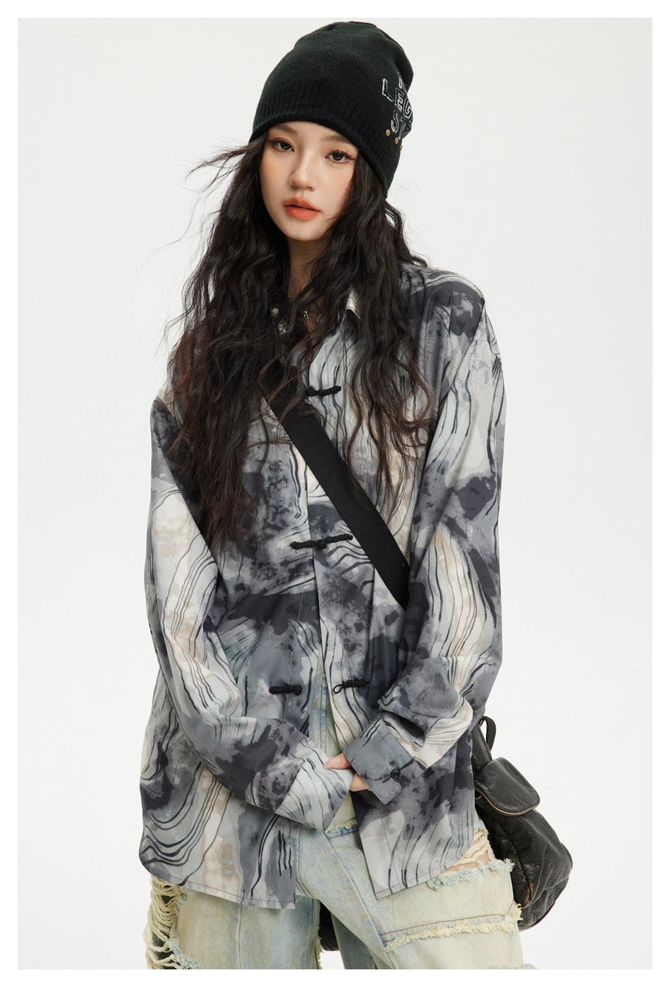 Front view of a model wearing an oversized gray abstract-print shirt with black frog closures.