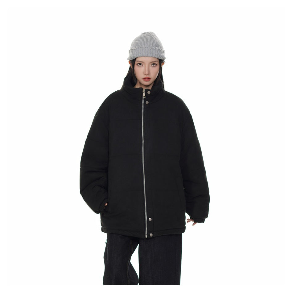 Model wearing an oversized black quilted jacket with zipper and snaps, gray beanie and dark pants, front view