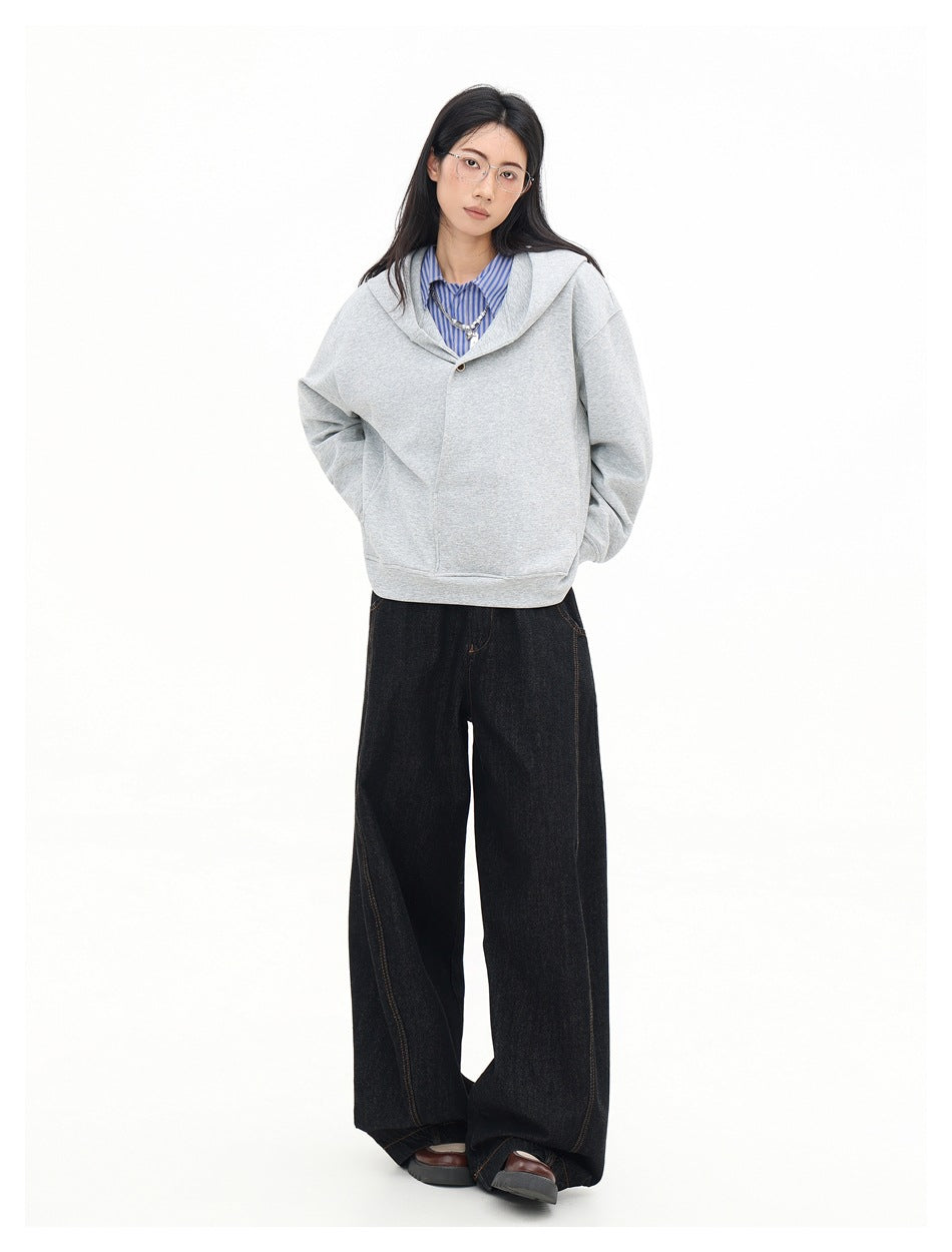 Front view of a model wearing a light gray oversized hooded sweatshirt with a buttoned crossover neckline.