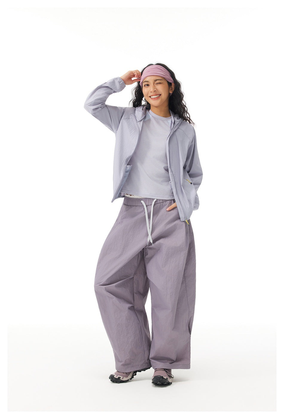 Full-length model wearing a pale lavender jacket, matching wide-leg pants, and a pink headband.