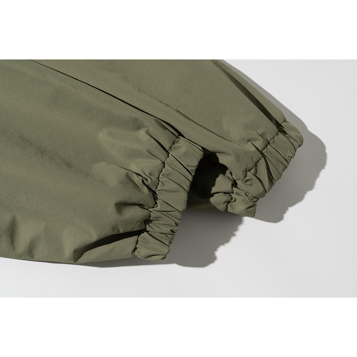 Close-up of an olive jacket sleeve with a gathered elastic cuff.