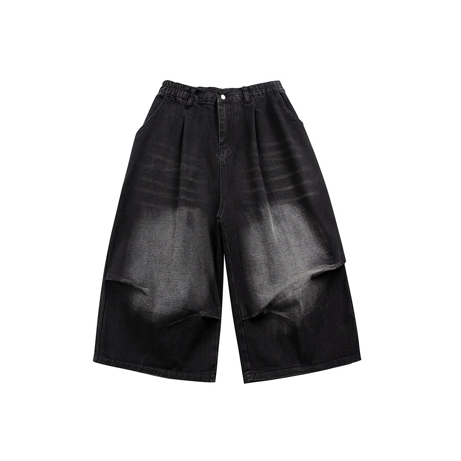 Black faded denim wide-leg knee-length shorts, front flat lay, with pleats and washed light fading on the thighs