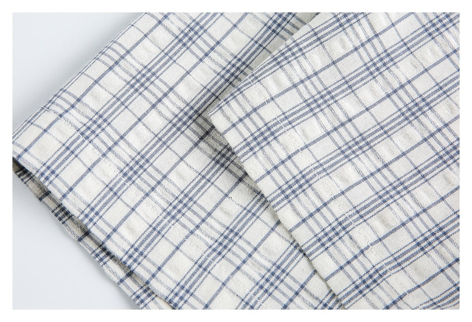 Close-up of a cuff and folded sleeve on a blue-gray plaid shirt.