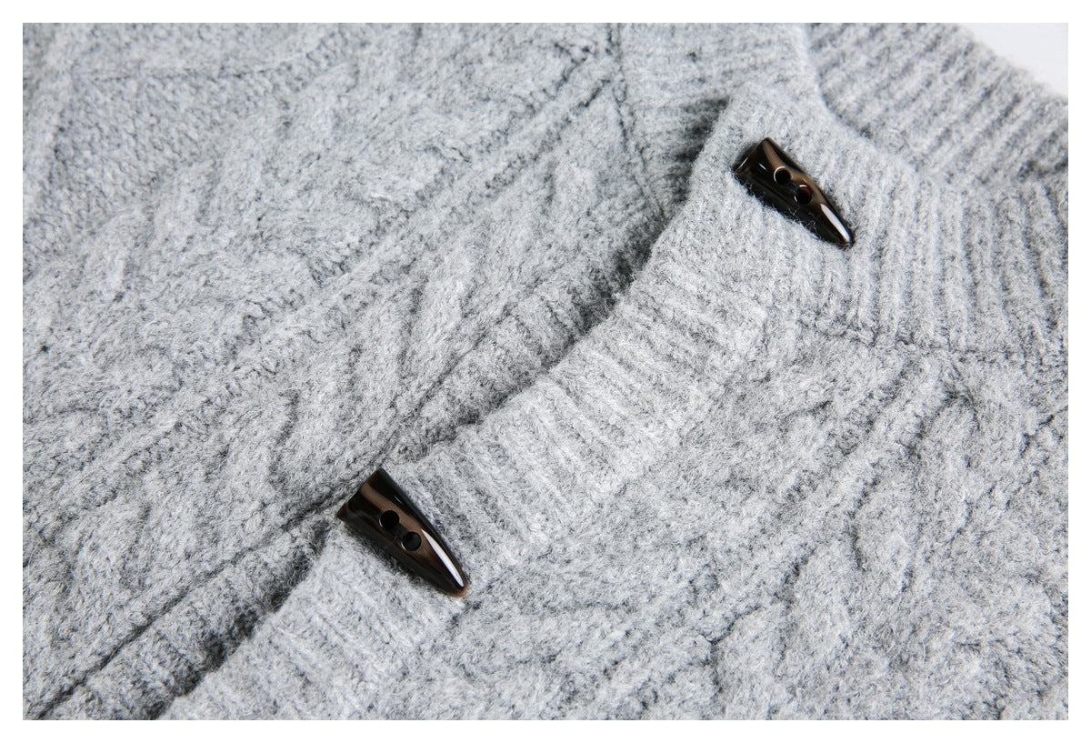 Close-up of a light gray cable-knit sweater's textured knit, ribbed collar, and dark toggle buttons.