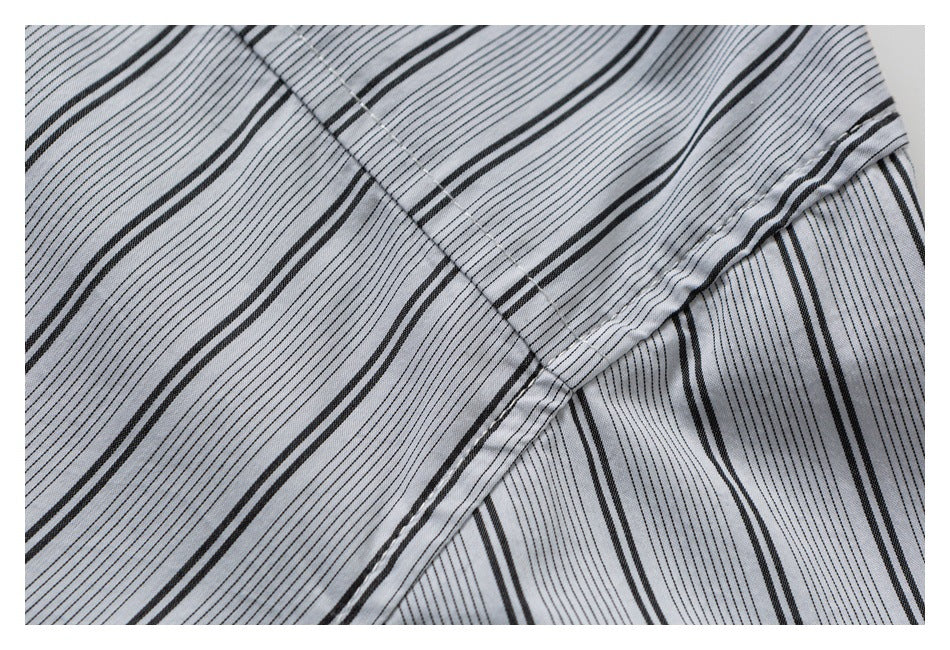 Close-up of light gray fabric with black stripes, overlapping panels, and visible stitching.