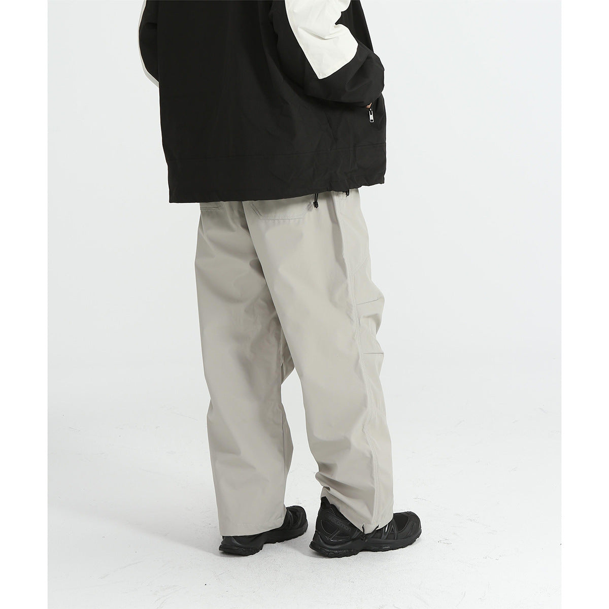 Rear three-quarter view of a person wearing light gray cargo pants with black shoes; upper body is cropped.