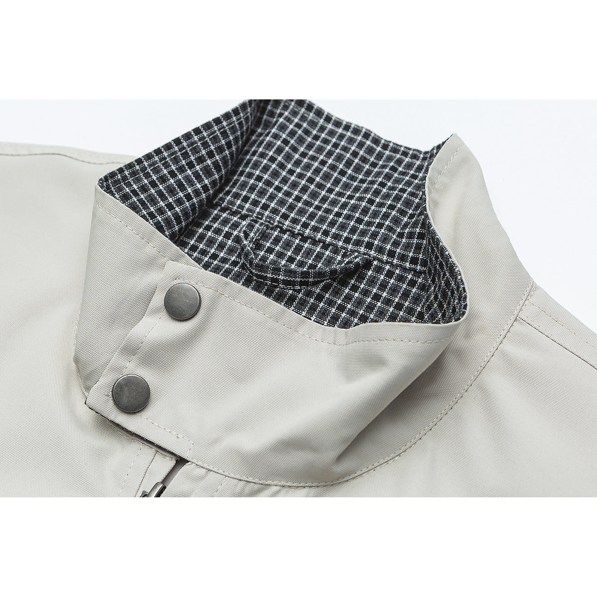 Close-up of an off-white jacket collar with black-and-white checked lining and two dark snap buttons.