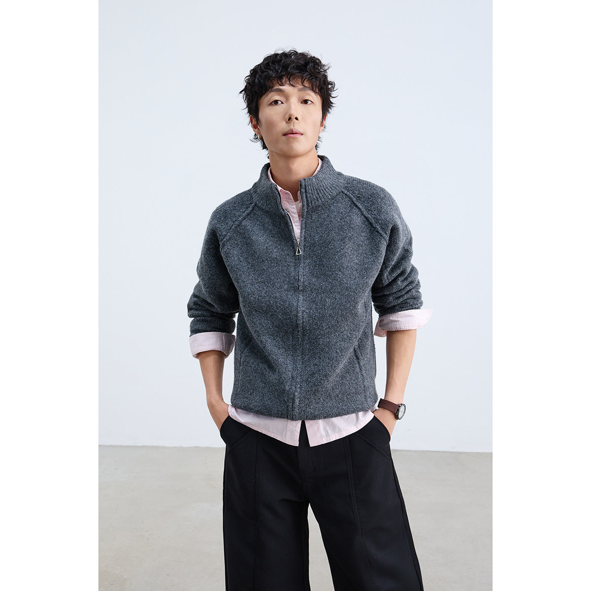Model wearing a charcoal gray zip-front knit jacket with a ribbed stand collar over a pale pink shirt.