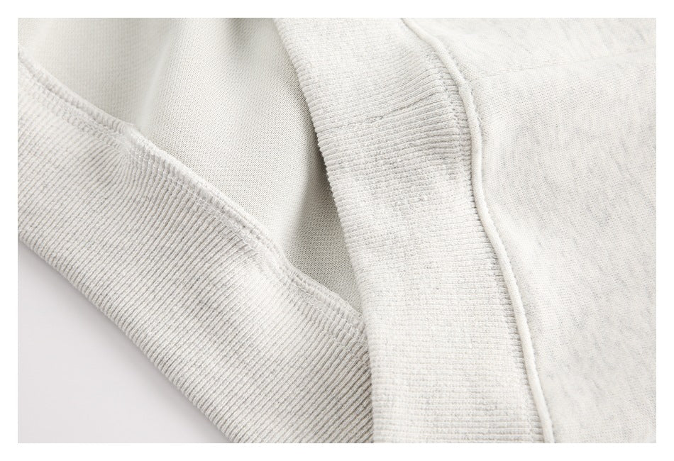 Close-up of the sweatshirt's ribbed trim, seams, and inner fabric in light heather gray.