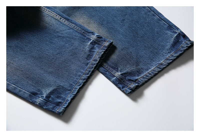 Close-up of the lower legs and hems of blue faded jeans laid flat.
