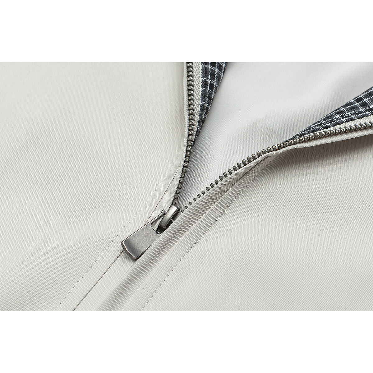 Close-up of the off-white jacket's metal front zipper and checked inner trim.