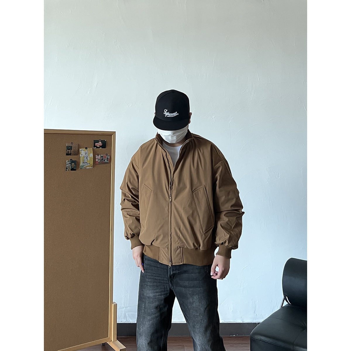 Front view of a person wearing a brown zip-front jacket with a high collar, slanted pockets, and ribbed trim.