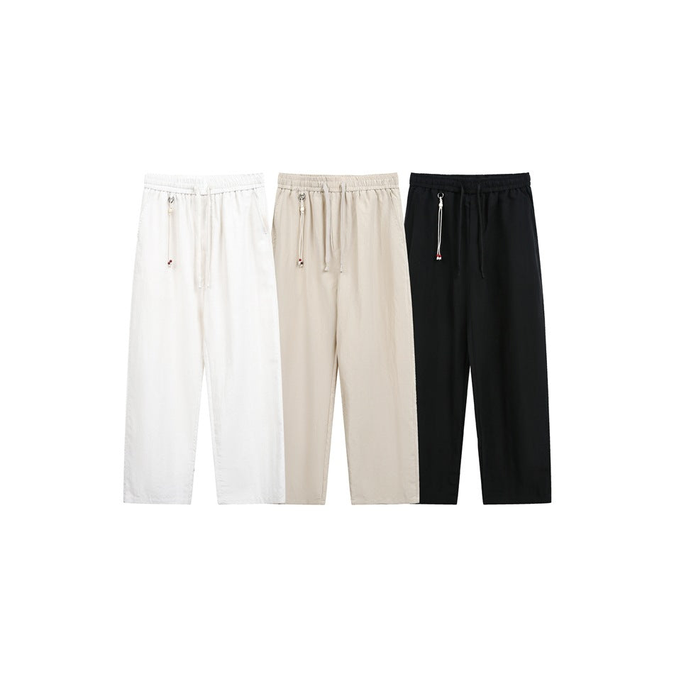 Front view of three pairs of relaxed pants in white, beige, and black, each with an elastic waist and drawstring.
