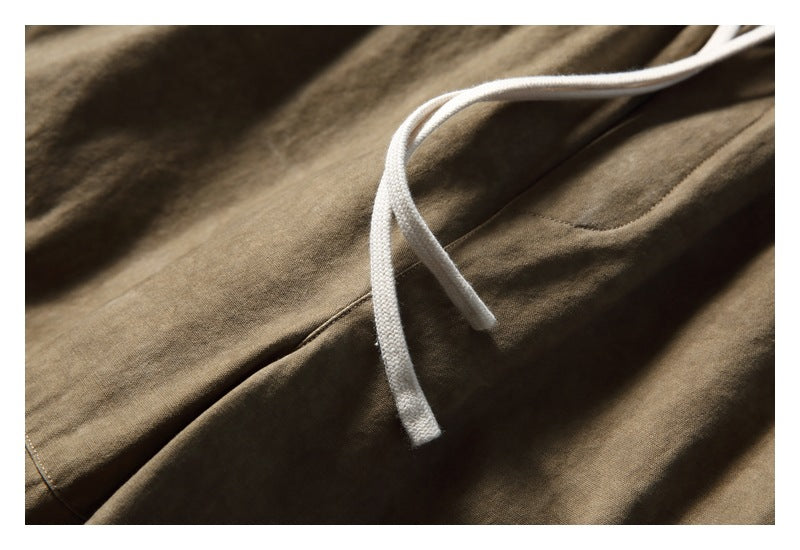 Close-up of white drawstrings against the olive-brown fabric of the pants.