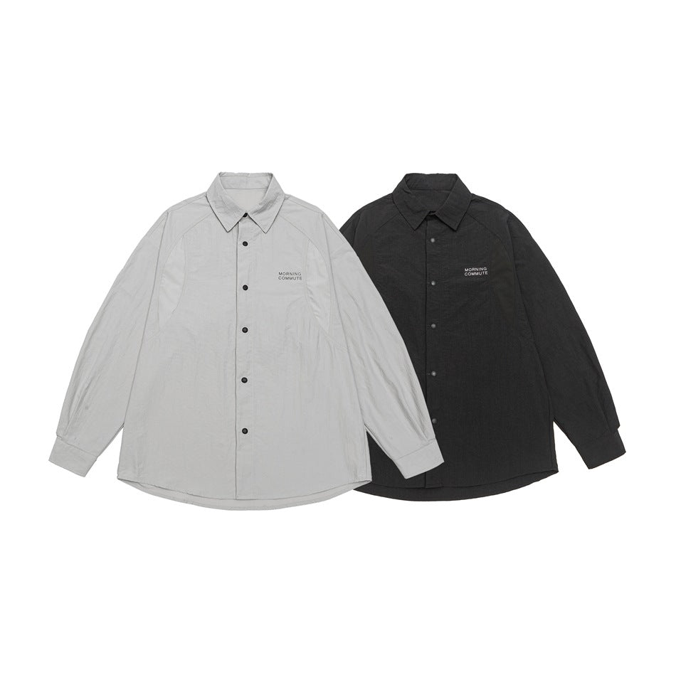 Two flat-lay collared button-up shirts shown together in light gray and black, each with small chest lettering.