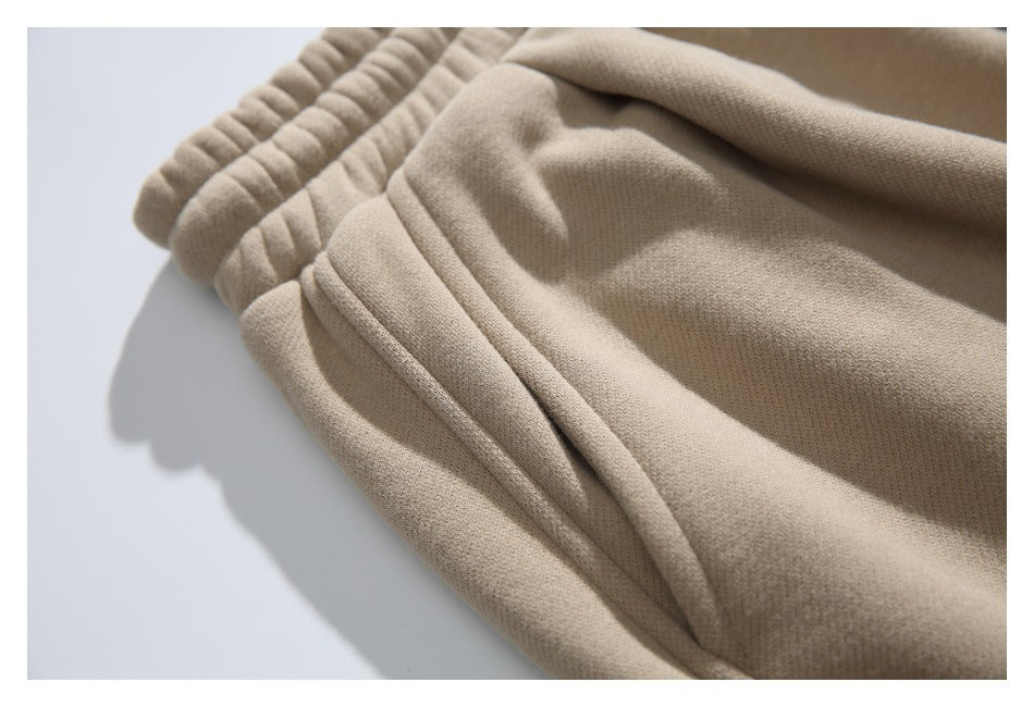 Close-up of beige jogger pants showing the gathered elastic waistband, pocket seam, and fabric texture.