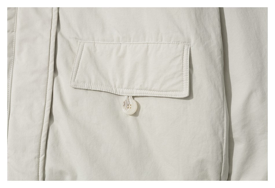 Close-up of an off-white jacket's flap pocket and button.