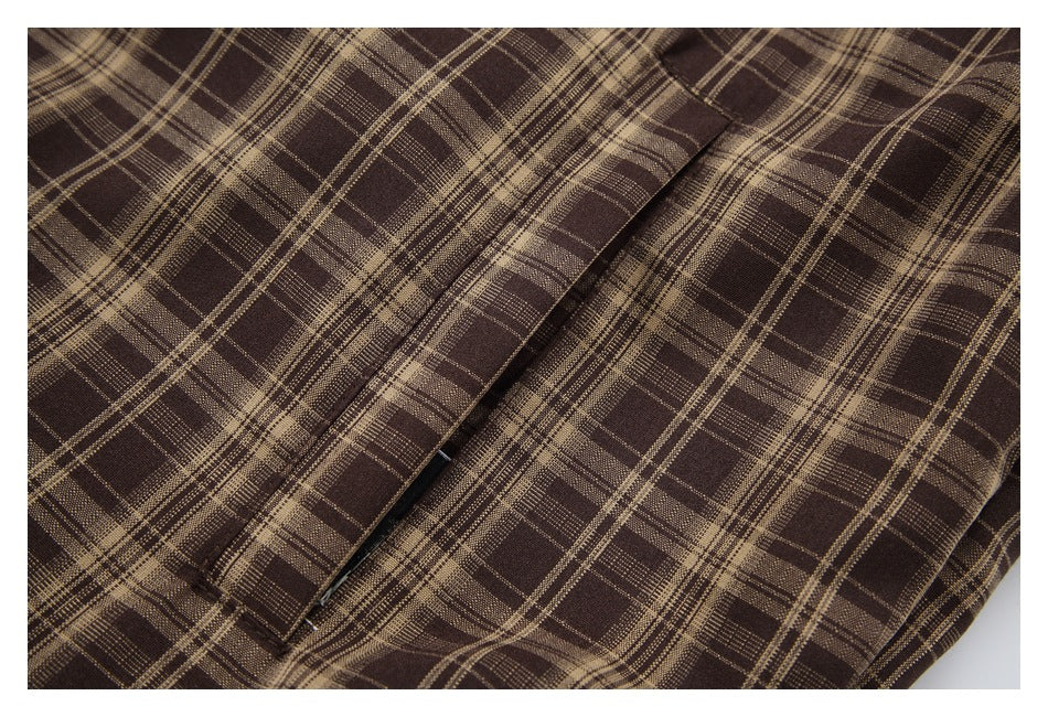 Close-up of brown plaid fabric and a slanted zip pocket on the jacket.