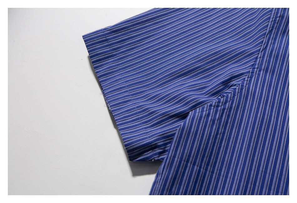 Close-up of a blue shirt with narrow white and dark stripes, showing a folded sleeve and stitching.