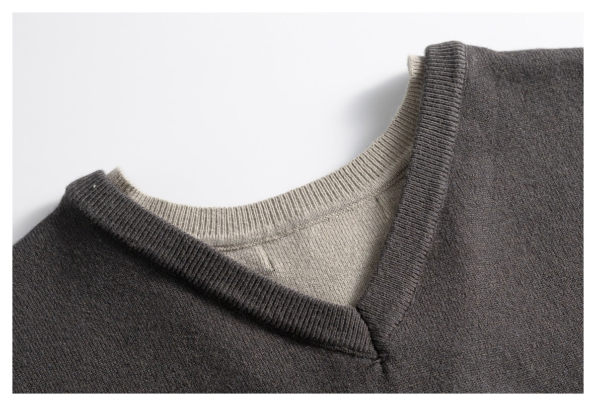 Close-up of a charcoal V-neck sweater layered over a light taupe crew-neck knit.