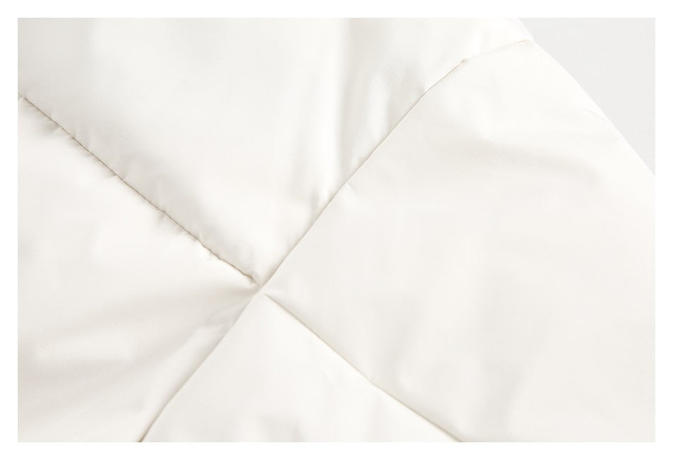 Close-up of intersecting stitched seams on off-white garment panels.