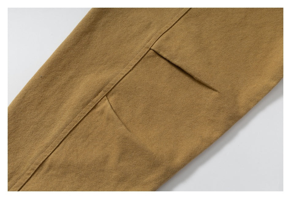 Close-up of a mustard-brown garment panel with diagonal seams and dart-like folds.