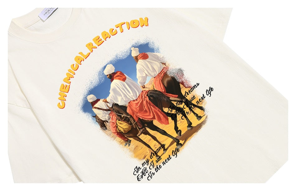 Close-up of an ivory T-shirt printed with riders on horseback, yellow lettering, and black script.