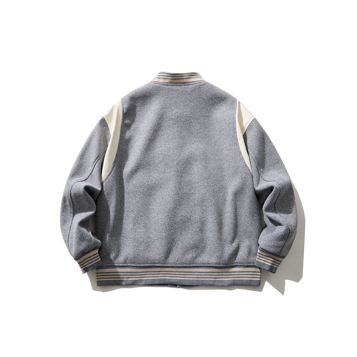 Back view of a gray varsity jacket with cream shoulder panels and cream-and-charcoal striped ribbed trim.