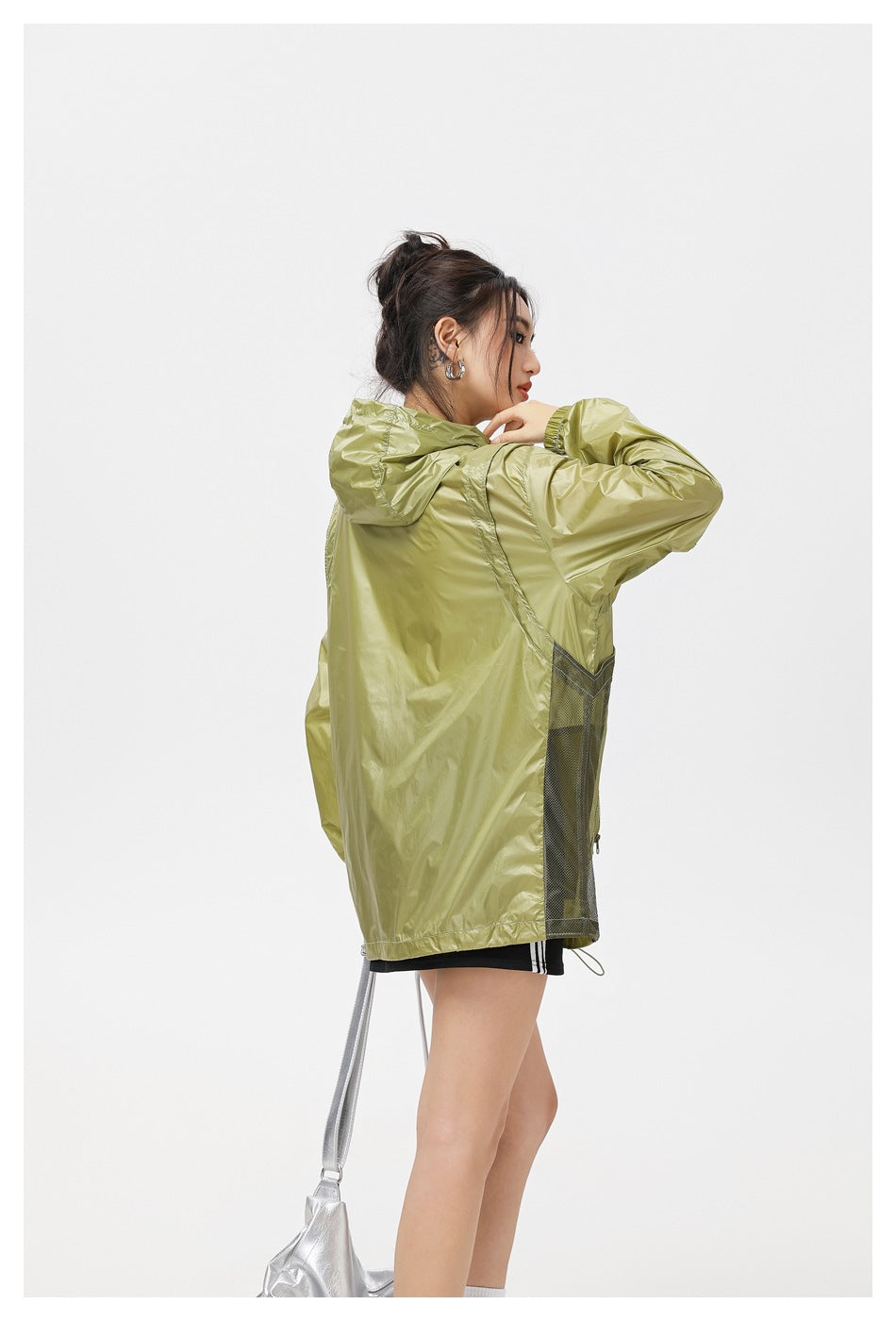 Side and back view of a model wearing an olive hooded jacket with dark mesh panels along the sides.
