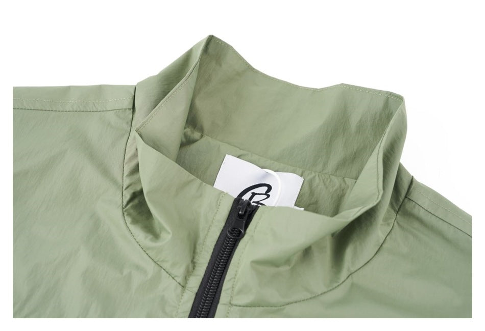 Close-up of a sage green jacket’s stand collar and black front zipper, with a small neck label.