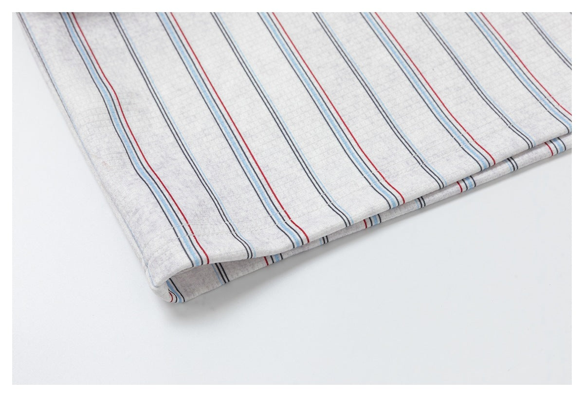 Close-up of the folded hem of light gray fabric with thin red, blue, and dark stripes.