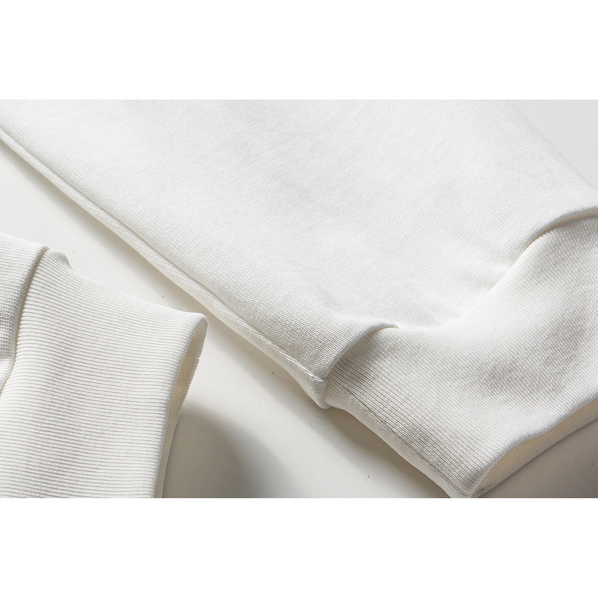 Close-up of white long sleeves with ribbed cuffs.