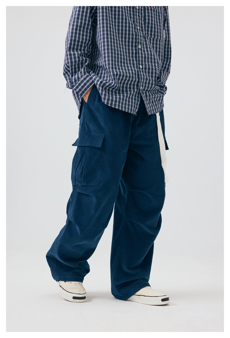 Three-quarter view of a model wearing loose navy cargo pants with a thigh pocket and a long light-colored drawstring.
