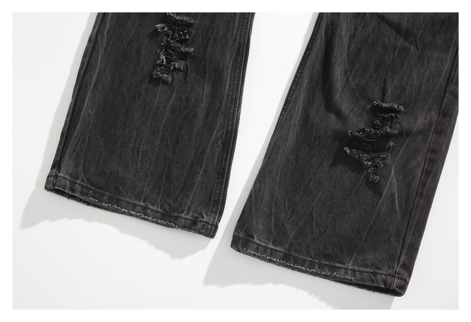 Close-up of the distressed lower legs and hems of black washed jeans.
