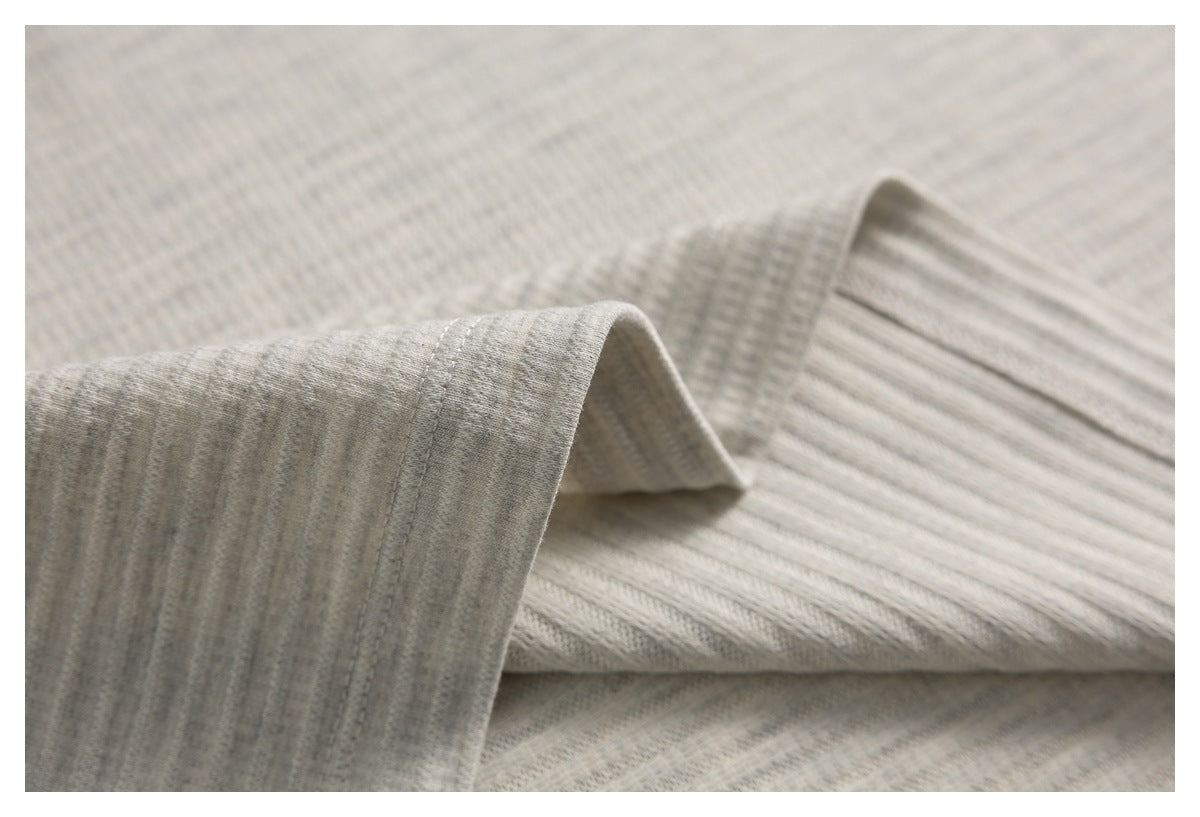 Close-up of a folded sleeve edge and textured light heather-gray knit fabric.