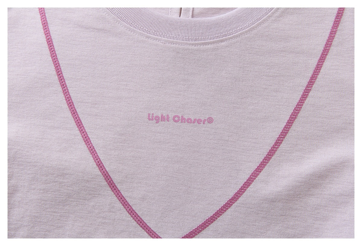 Close-up of a pale lavender top with pink neckline stitching and small pink “Light Chaser®” chest print.