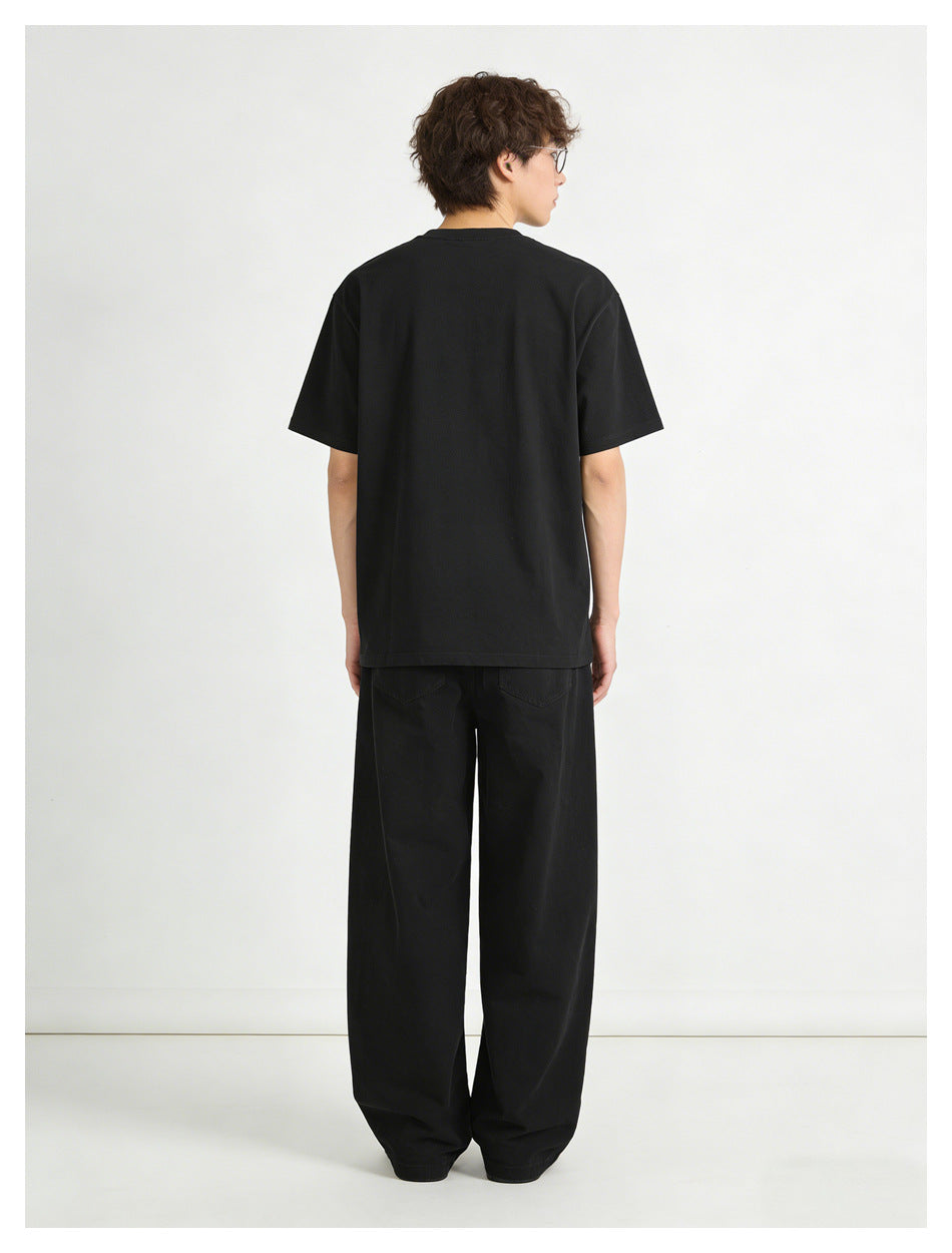 Rear view of a model wearing a plain black T-shirt and loose black pants with back pockets.