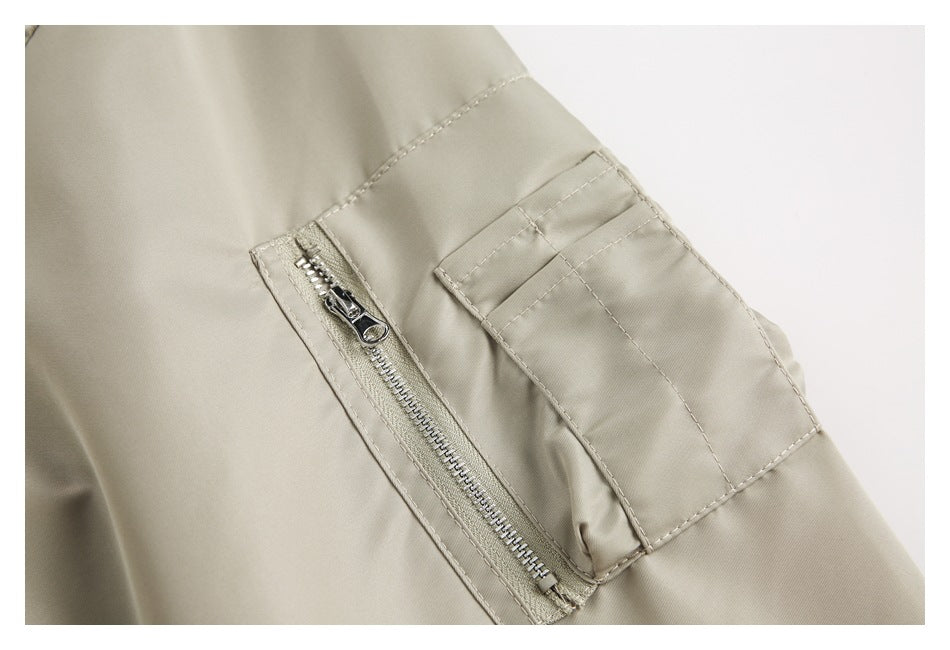 Close-up of a beige jacket sleeve with a zip pocket and stitched flap utility pocket.