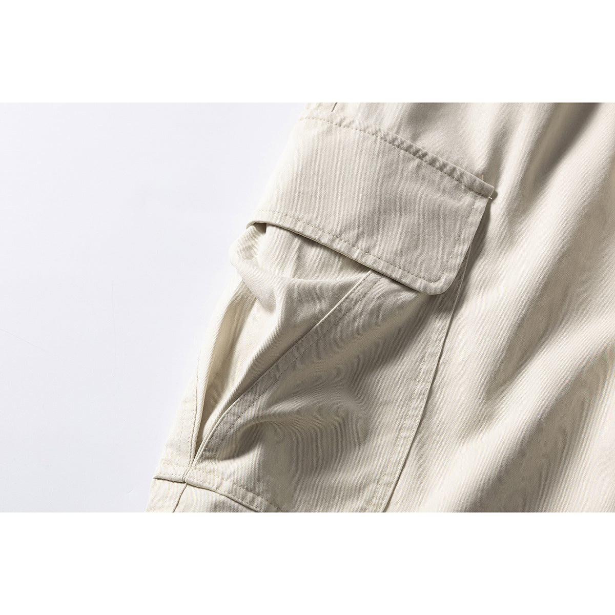 Close-up of a cream shorts cargo pocket with a flap and visible stitching.