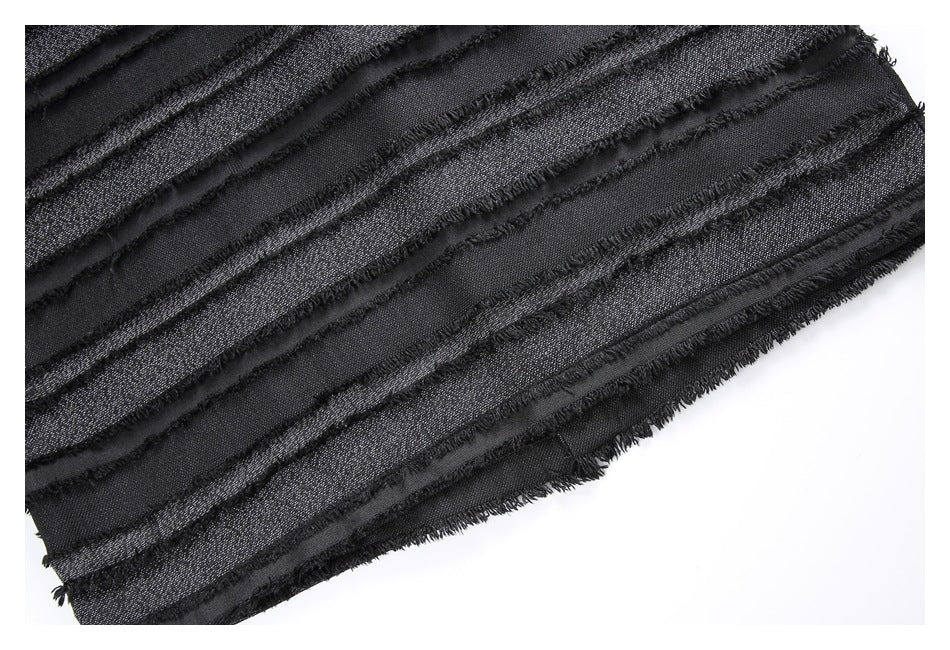 Close-up of a black garment section with repeated fringed bands and a faint metallic texture.