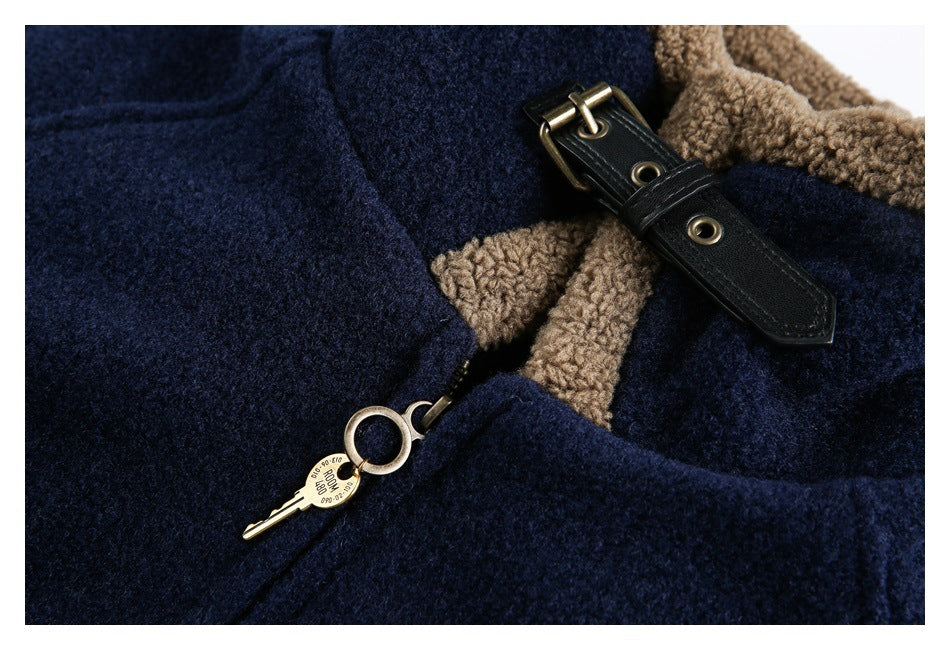 Close-up of a navy jacket showing its tan collar trim, black buckle strap, and brass zipper pull.