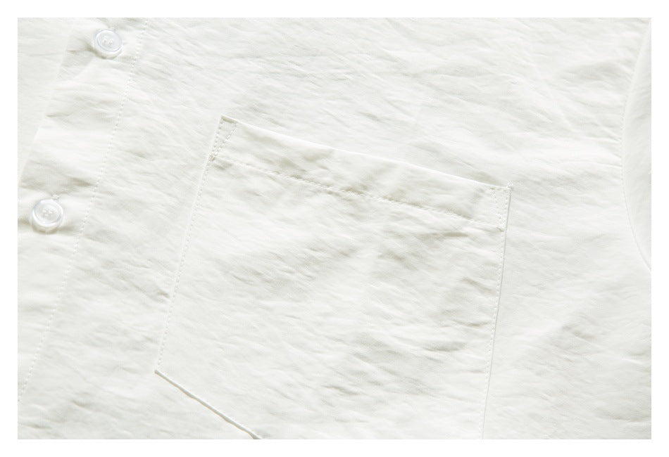 Close-up of an ivory shirt's chest pocket, white buttons, and textured fabric.